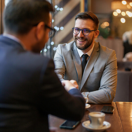 Zwei Männer schütteln Hände in einem Café