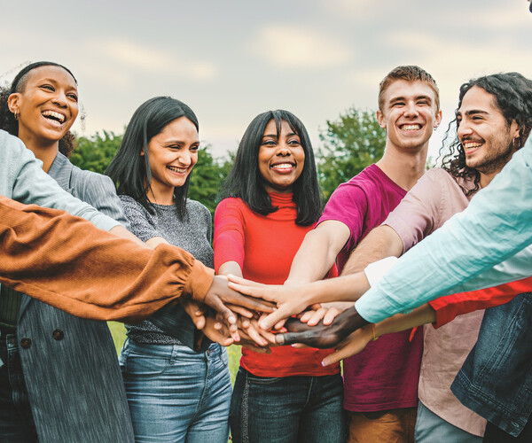 joyful team of multi-ethnic young people joining hands together - people diversity culture concept